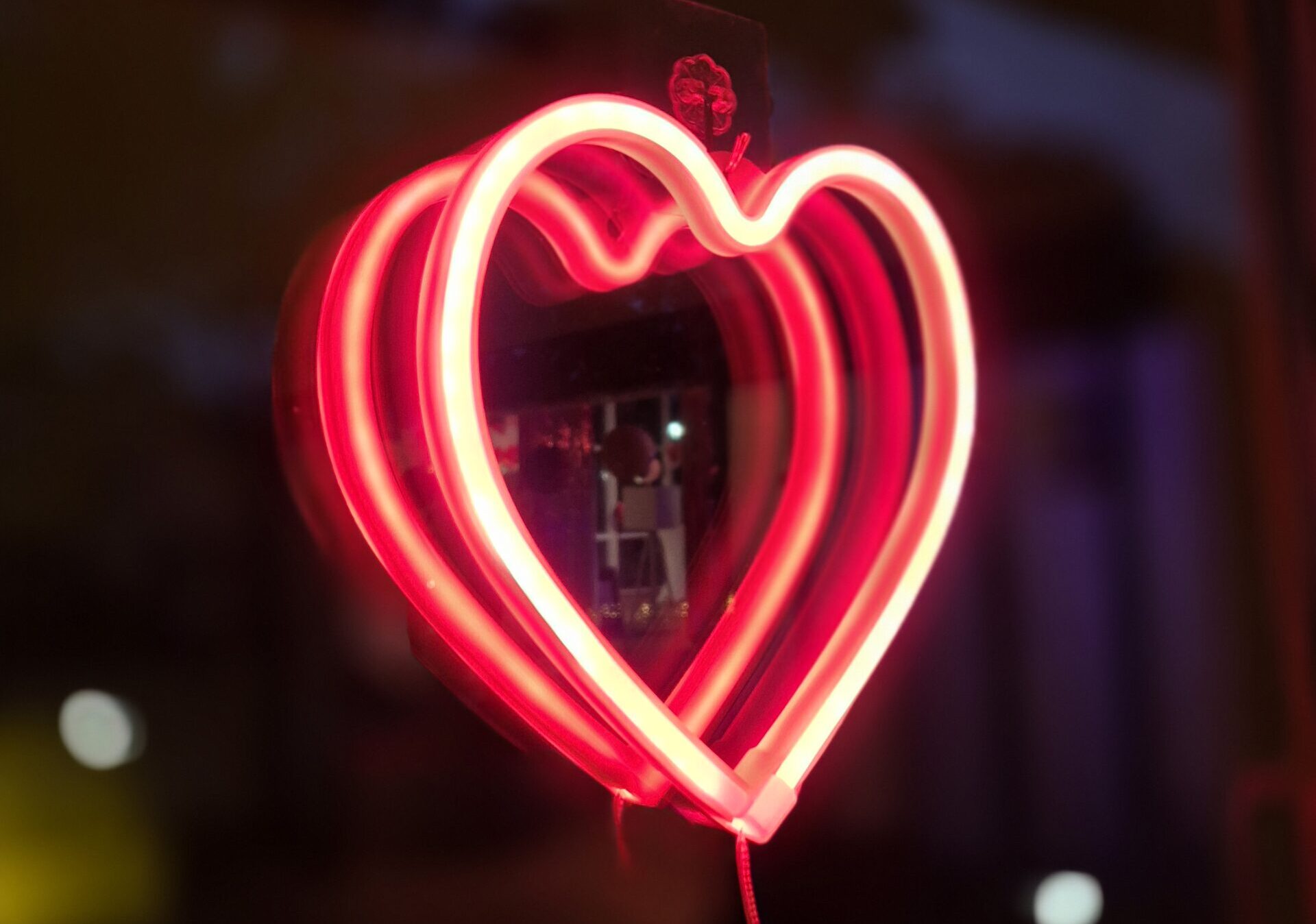 Leuchtendes Neonherz in Pink und Rot vor dunklem Hintergrund als Symbol für die Herzblatt-Party für Singles in Berlin.